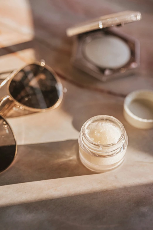 sunglasses, eye shadow container and eyeglasses are laying on a table