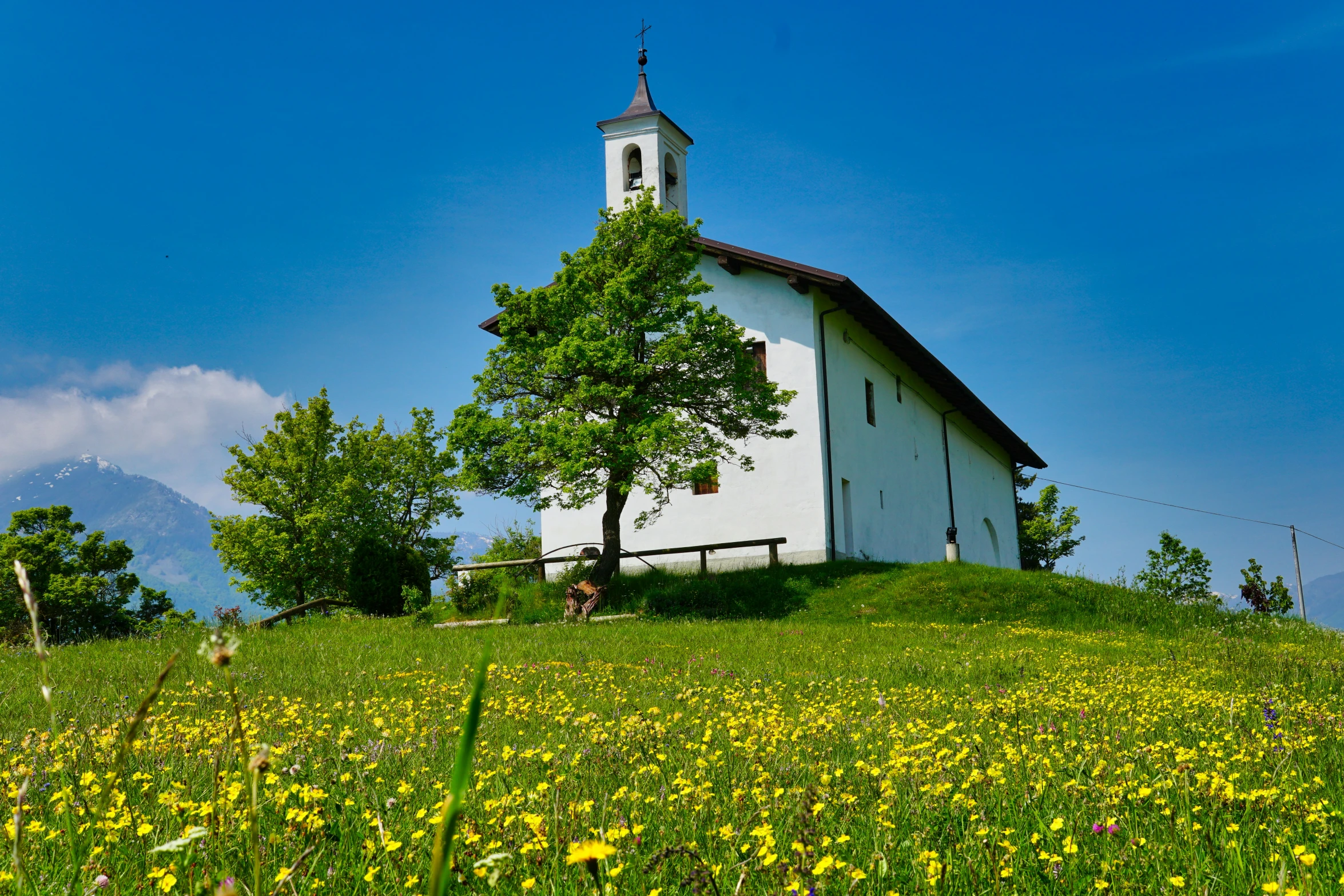 a small white church is standing on a grassy hill