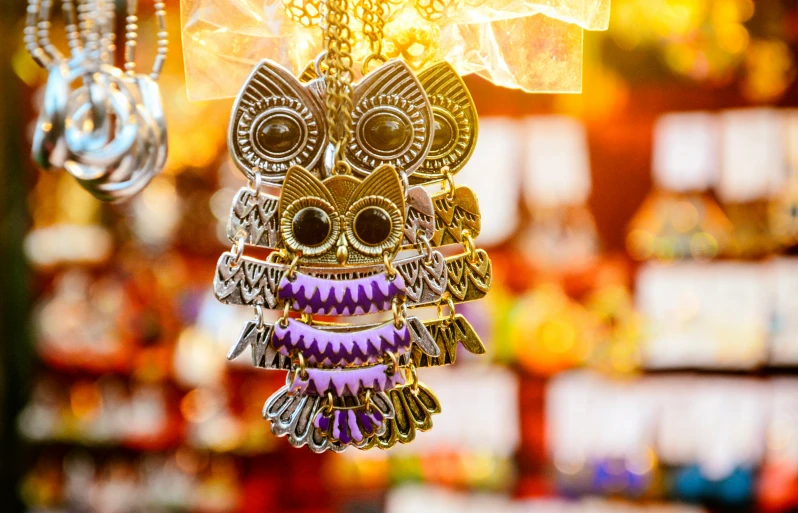 a hand holding three owls in gold and purple