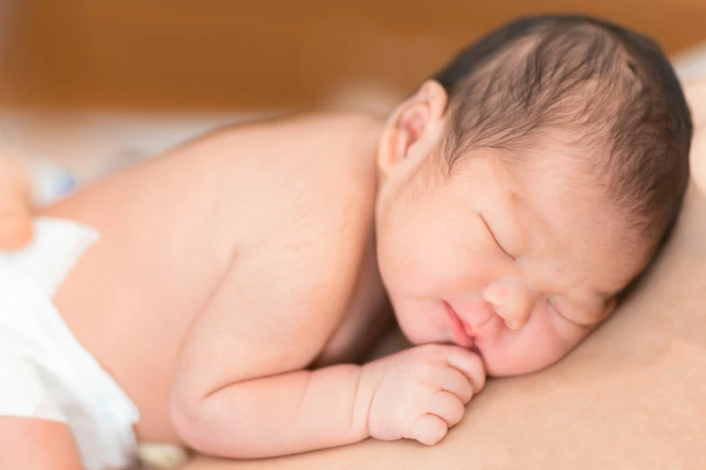 baby sleeping on blanket with hands tucked under the 