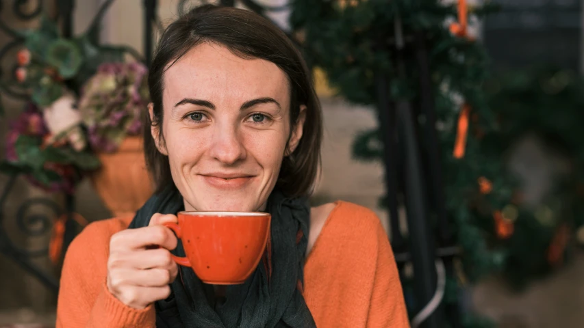 smiling woman holding coffee cup up to her face