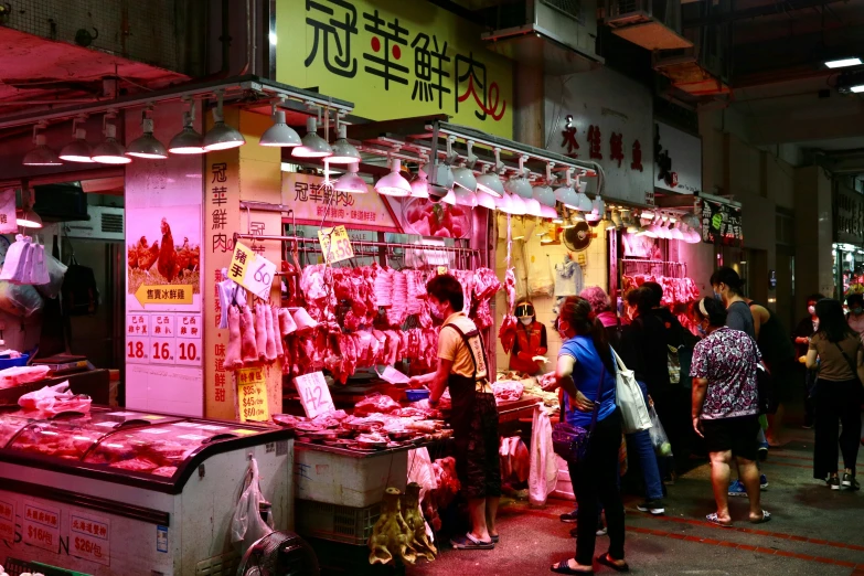 an asian food market with several patrons standing around the food