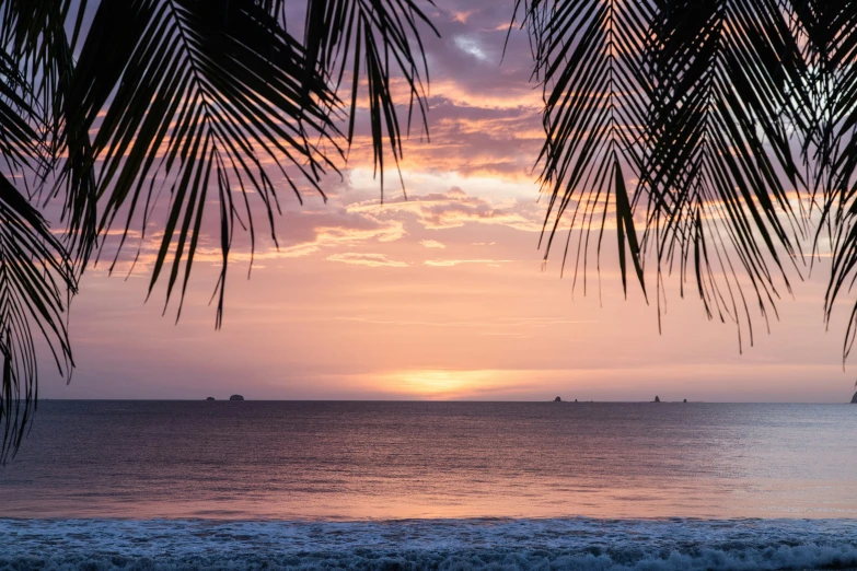 the sun is setting in the ocean and a boat out on the horizon