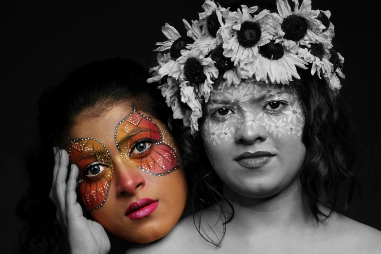 two women posing with flower heads, erfly wings and painted faces
