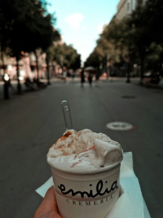 a person holds an ice cream dessert on a city street