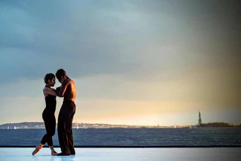 two women emcing in front of the ocean with a city in the background