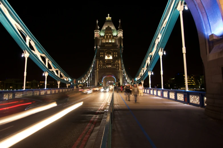 a view of a bridge at night with cars and light streaks