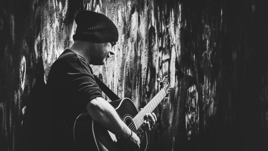 the man is playing his guitar by the wall