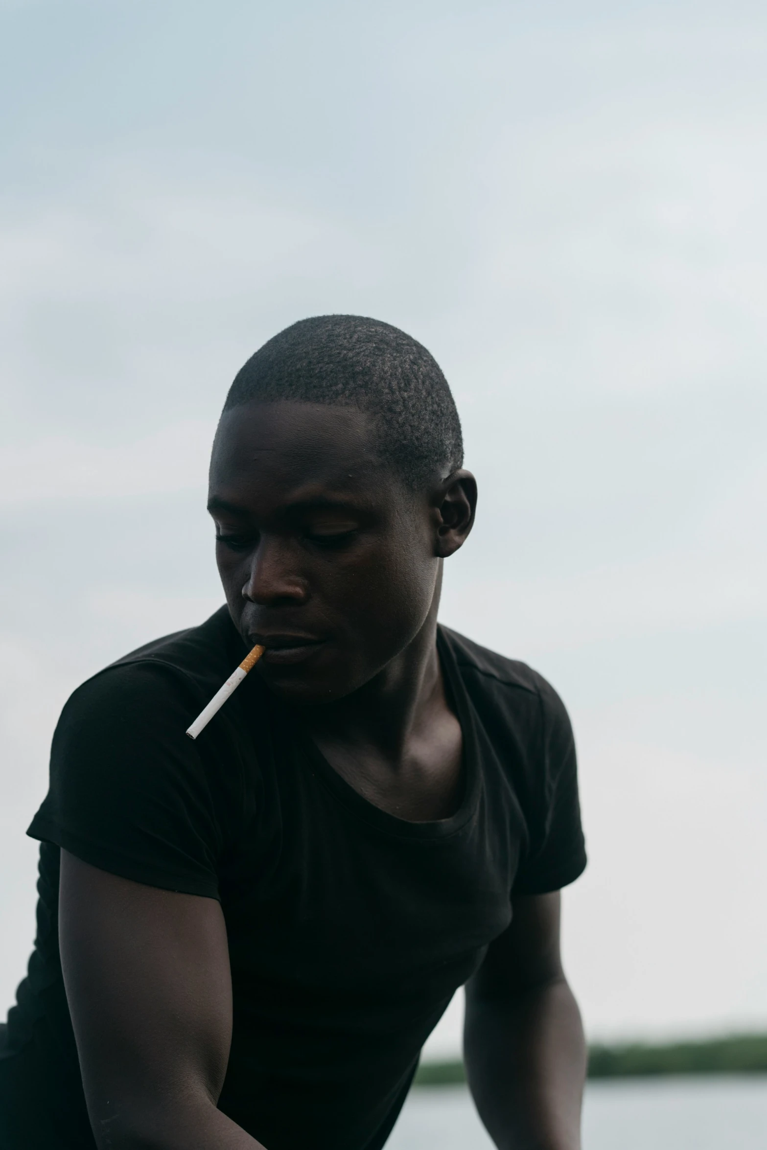 a black man holding a cigarette to his mouth