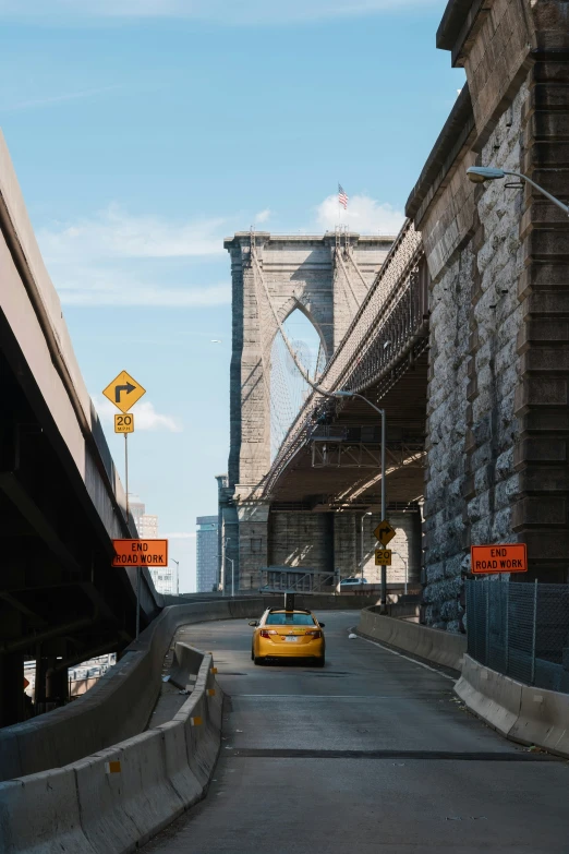 a view of an underpass with a street sign and a yellow car