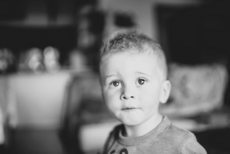 a little boy with a short beard and t - shirt looking into the camera