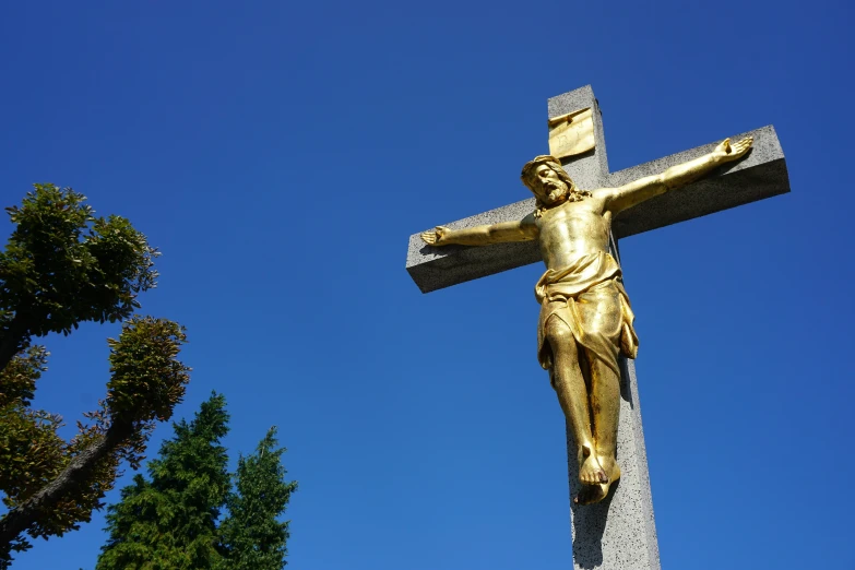 a gold cross sitting next to a tree