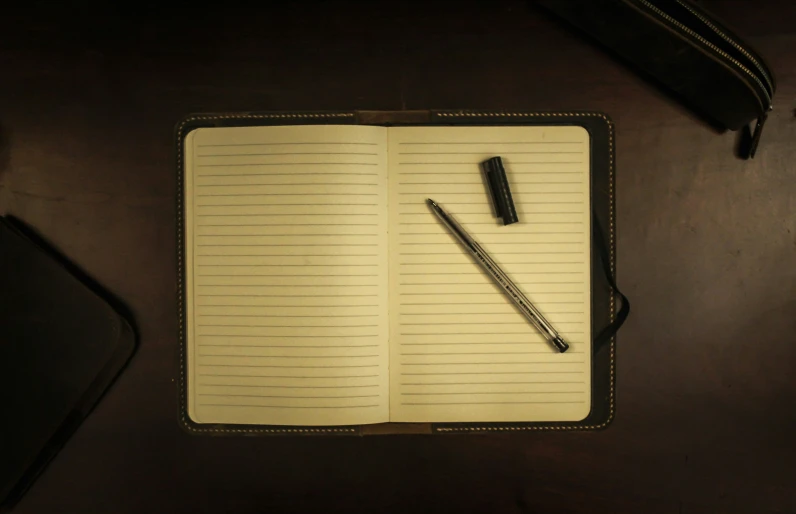 an open notebook and pen sitting on a table