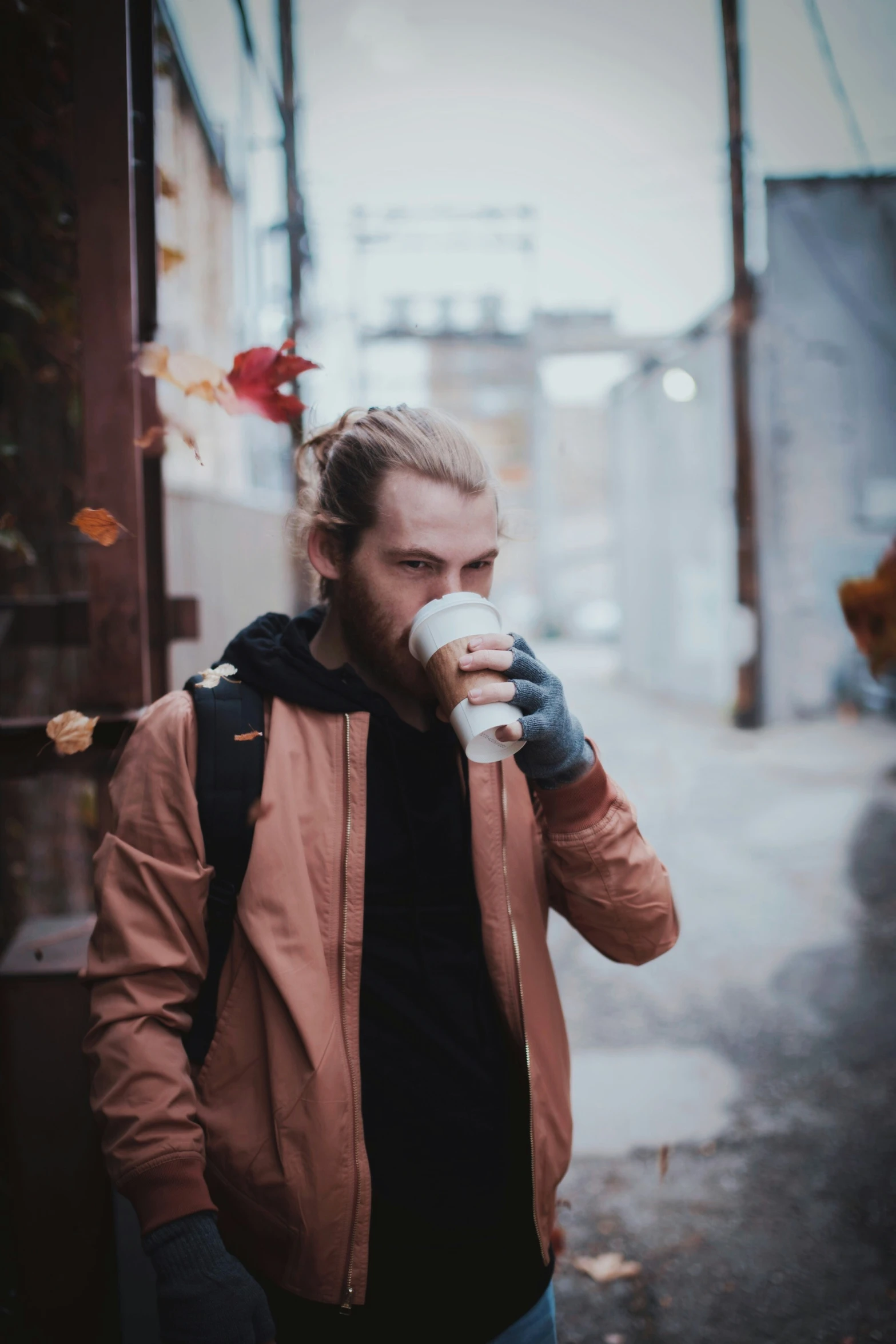a man standing on the sidewalk sipping from a cup