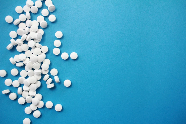 several white pills spilled on top of blue background