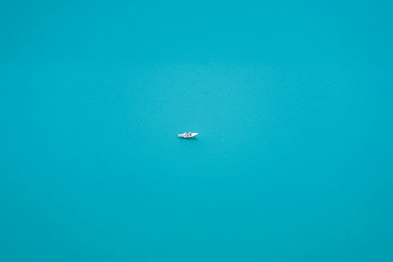 a small boat floating in the middle of a turquoise ocean