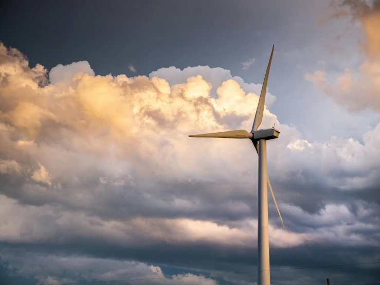 a wind turbine on an open field against a cloudy sky