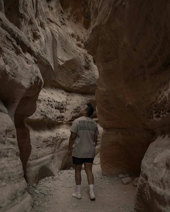 man standing in a cave at the base of a cliff