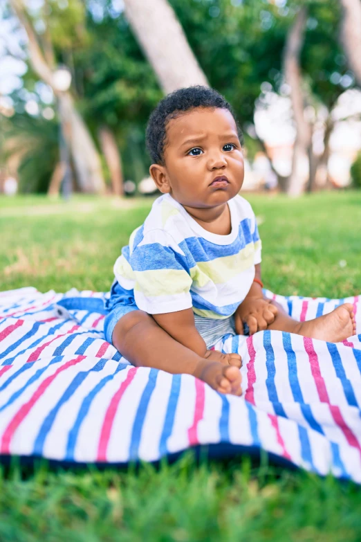 a small child laying on a blanket in the grass