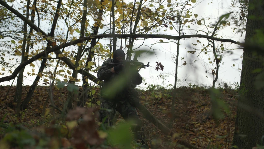 a soldier walking through the woods with a gun