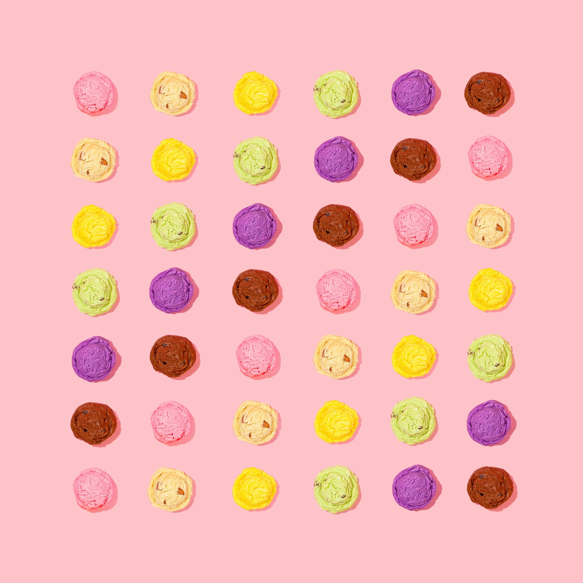 a number of donuts in rows on a pink background
