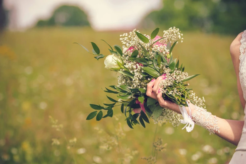 a bride holding a bouquet in a green field