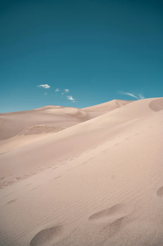 a lone car on the top of a big desert dune