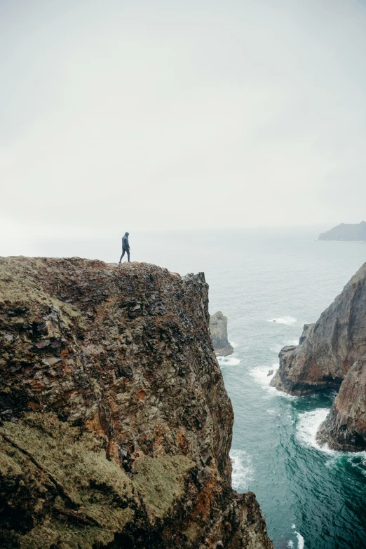 a person standing on the side of a cliff with water behind them