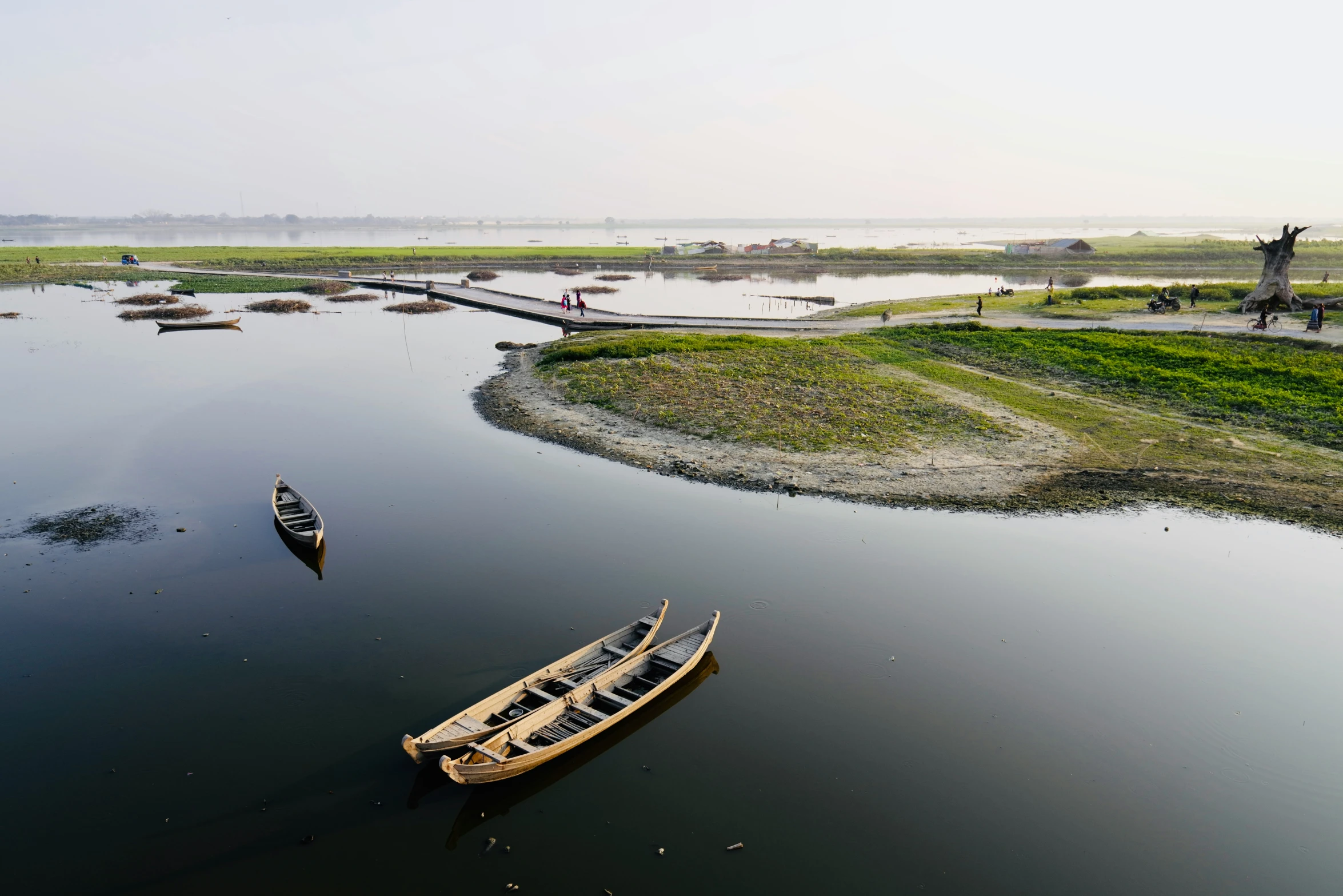 several small boats in the water near some people