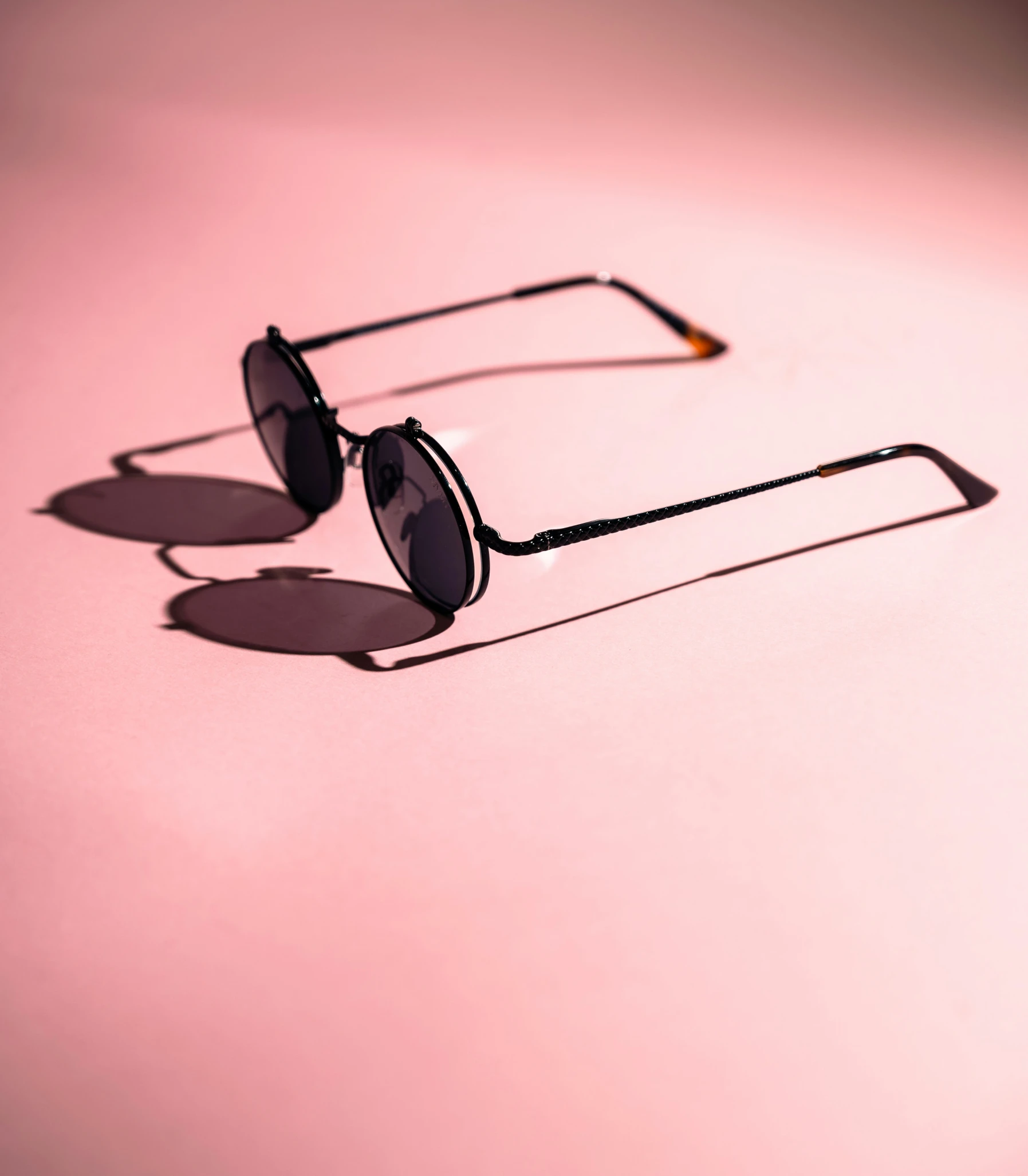 a pair of sunglasses sitting on top of a pink background