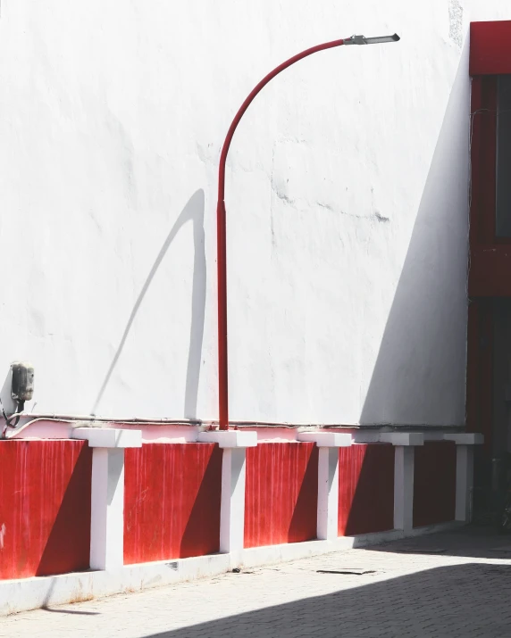a red and white wall with a street light and a red bench