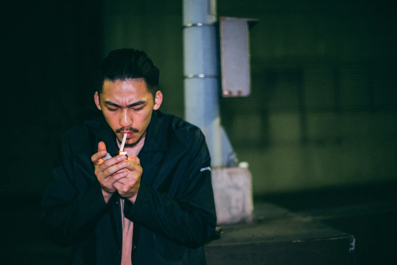 a man standing by a pipe lighting a cigarette