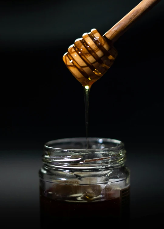 honey is pouring into a jar that's filled with honey