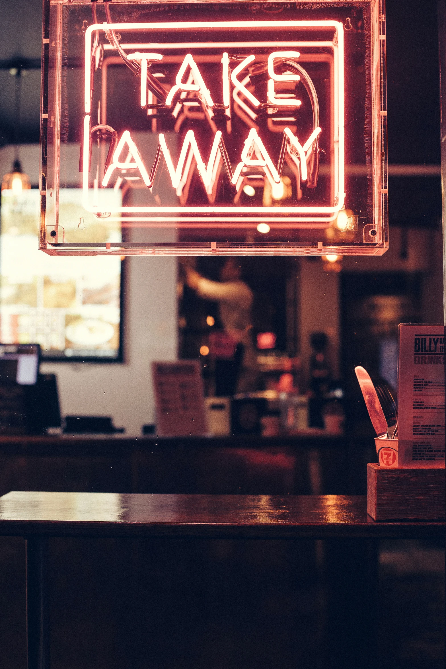 a neon take away sign is glowing with red light