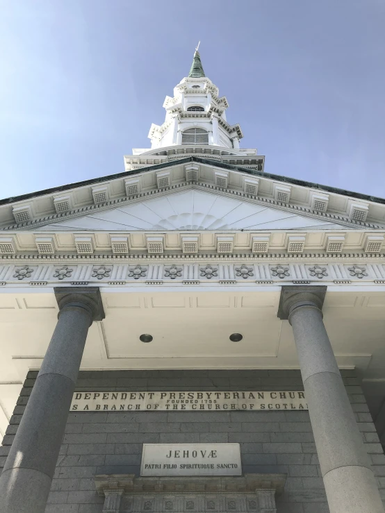 a white building with columns below a steeple and writing on the front