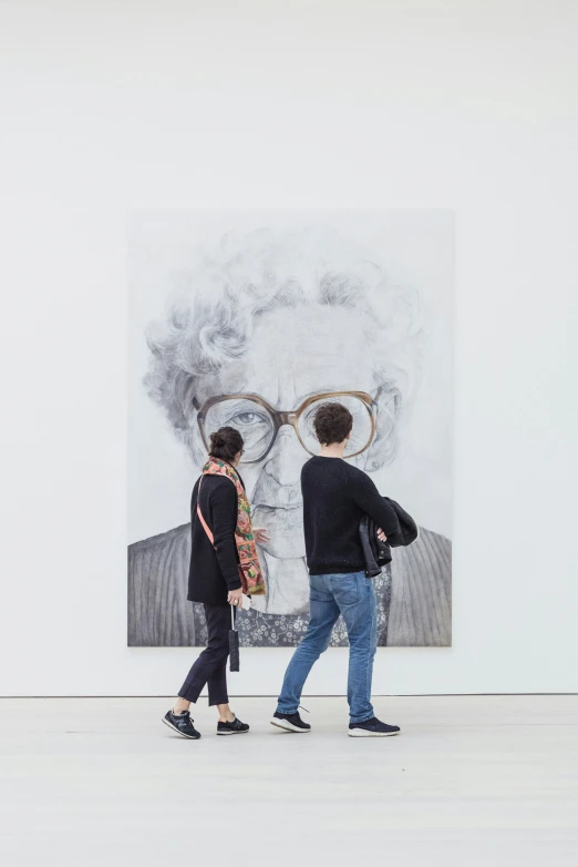 a couple standing next to each other in front of a painting