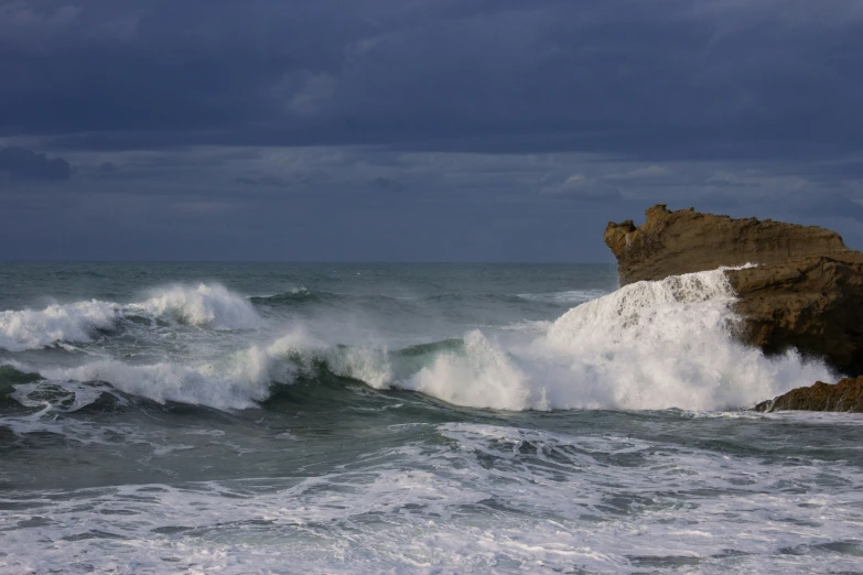 an ocean with waves crashing against a large rock