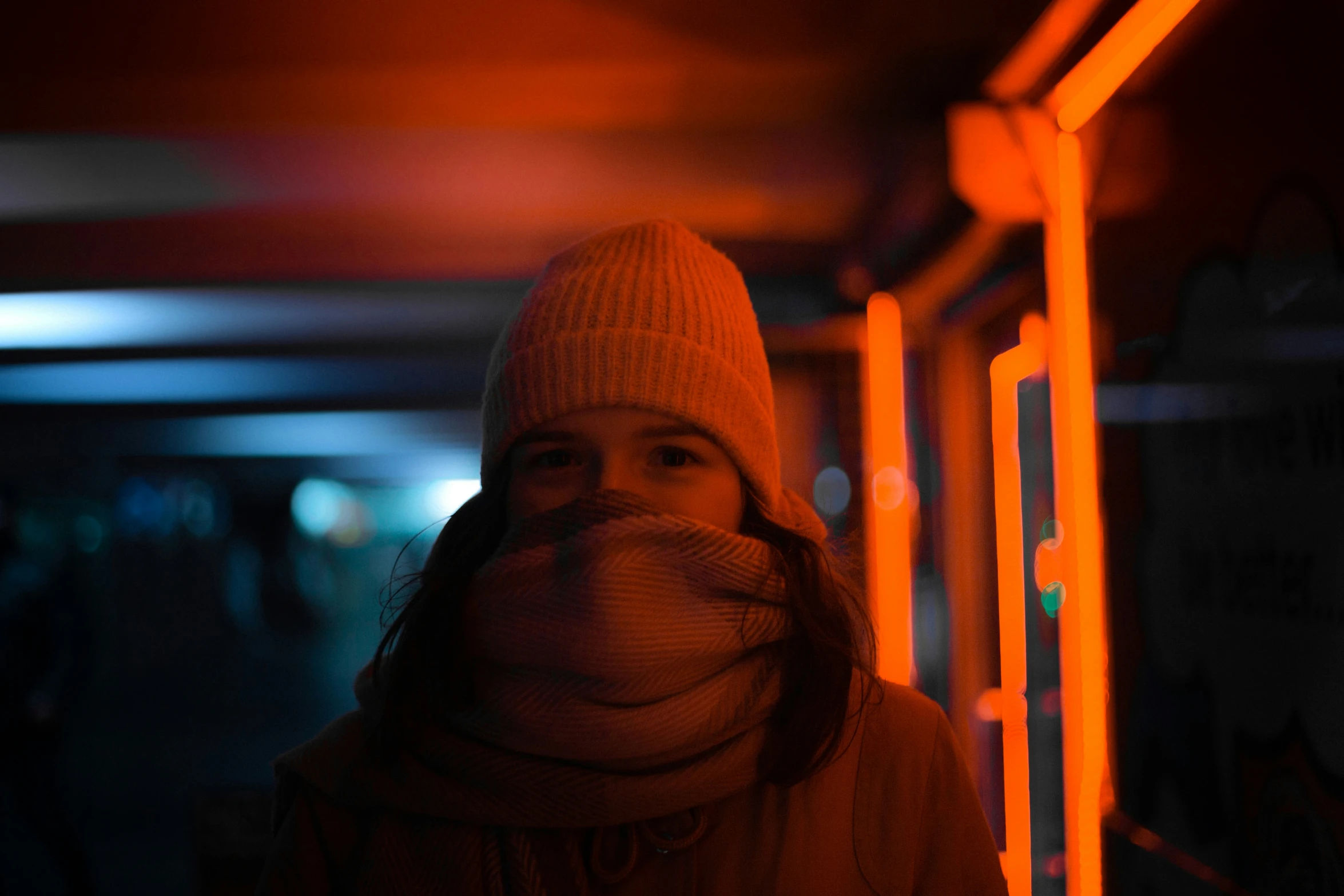 a person with a beanie standing under an orange light