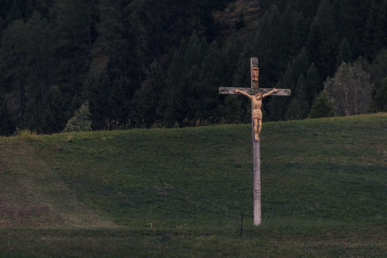 a wooden cross sitting in the middle of a grassy field