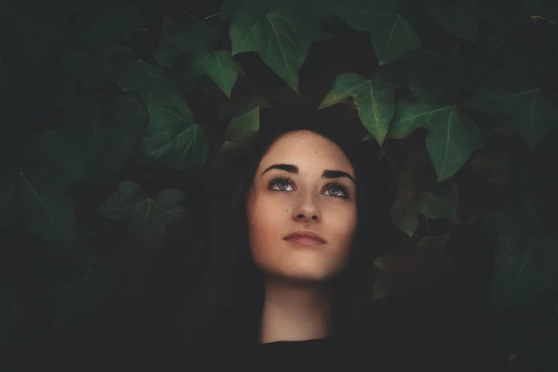 a woman stares at soing while laying down on leaves