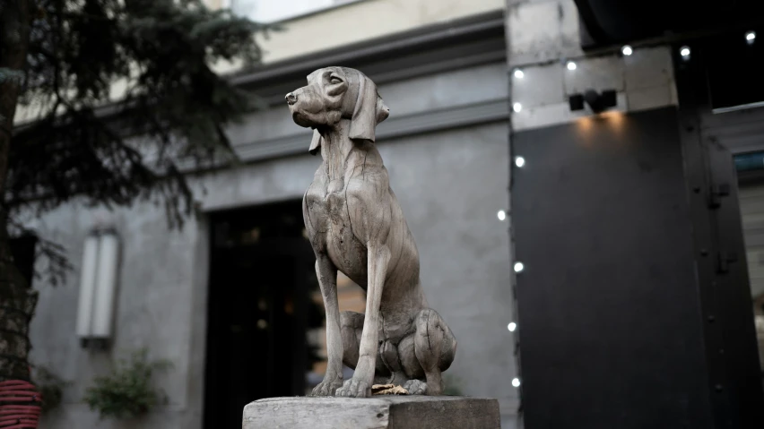 the statue of a dog is next to a tree