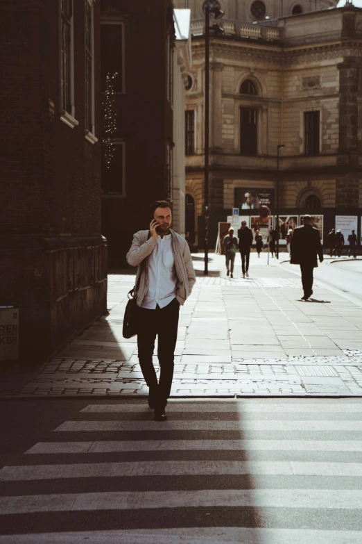 man walking in the street while holding onto his cellphone