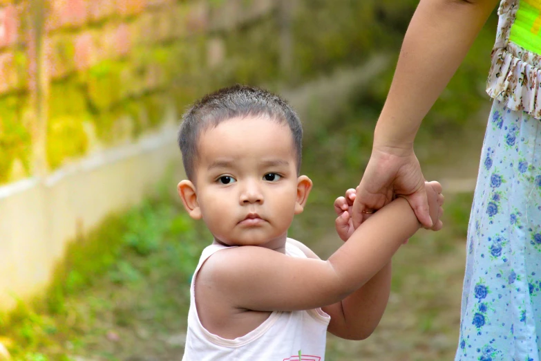 a little boy holding onto the hand of his mother