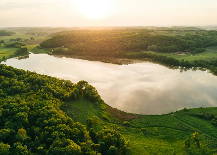 a lake sitting between trees and green fields