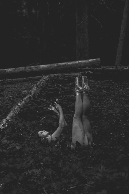 a woman laying down in the woods on her stomach