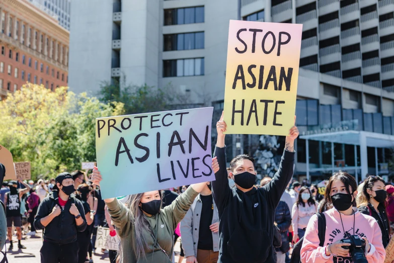 protesters hold signs and carry masks while marching on a street