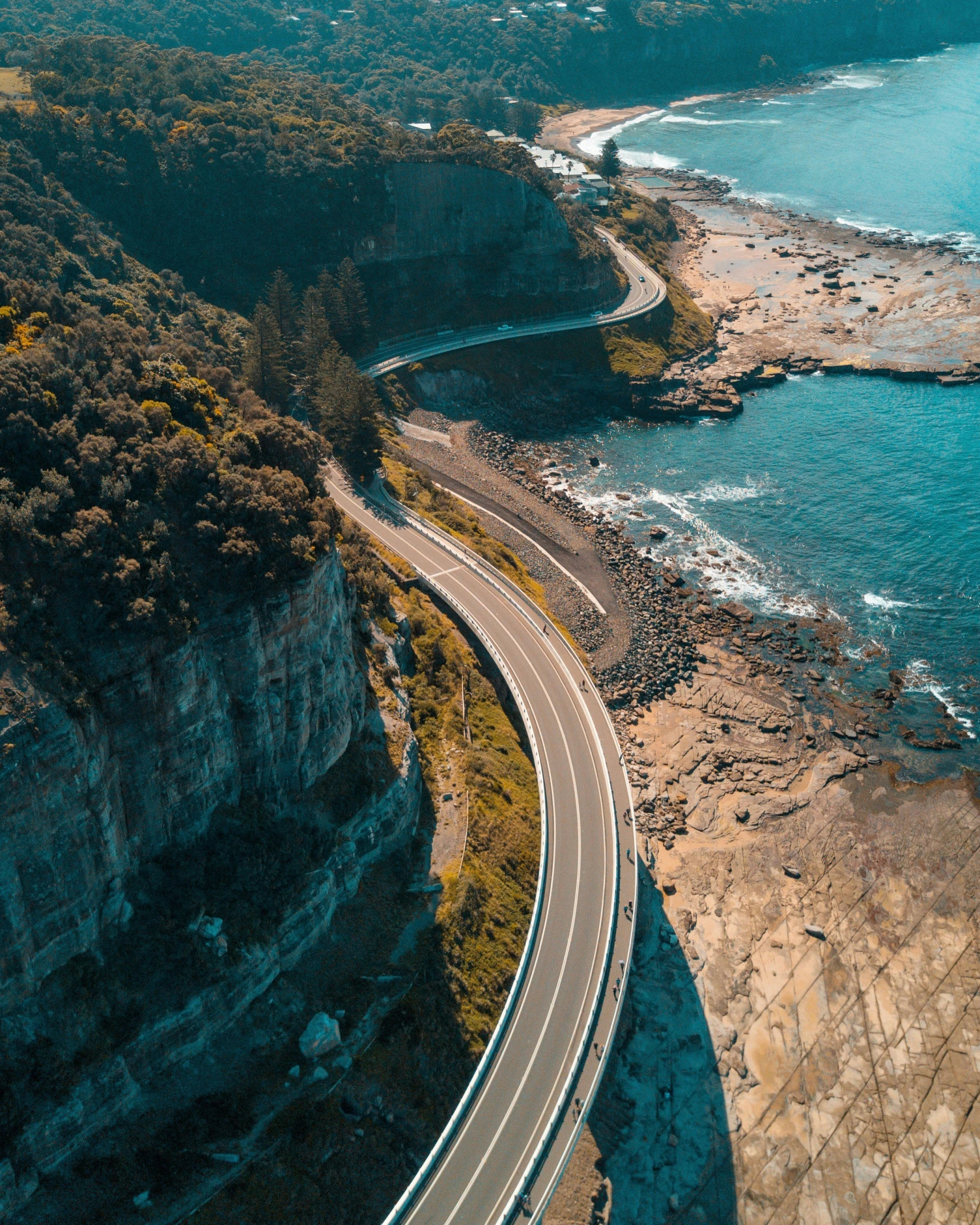 a winding highway that is next to some ocean