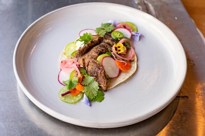 meat and vegetables on corn tortilla displayed on plate