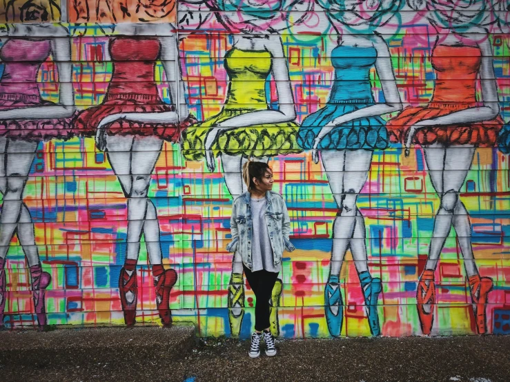 a girl standing in front of graffiti on a wall