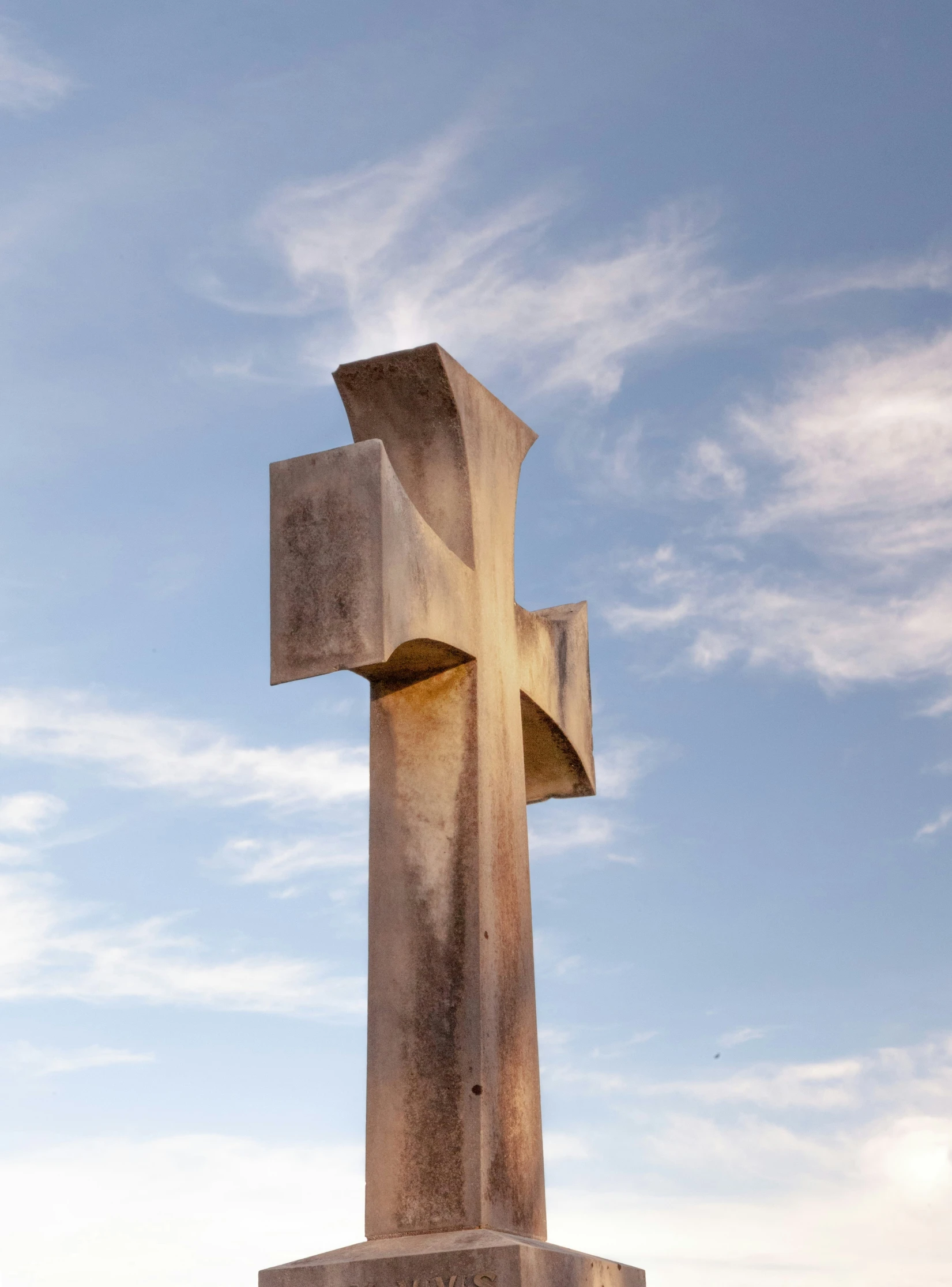 a tall cross standing on top of a cement wall